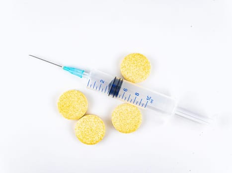 Medical syringe and pills on a white background.