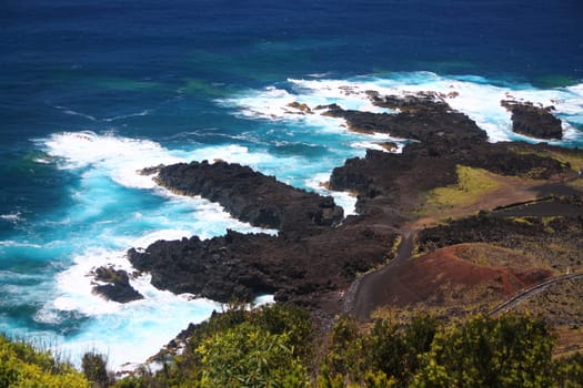 The intense blue sea and the black volcanic rocks