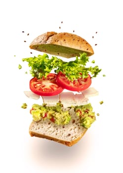 Exploded and flying vegetarian sandwich with guacamole and tofu cheese on white