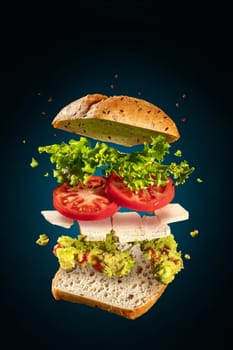 Exploded and flying vegetarian sandwich with guacamole and tofu cheese on blue