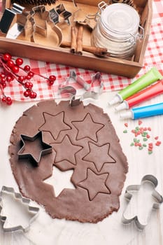 Decorating gingerbreads. Dough, rolling pin, shape cutter for handmade cookies, confection lying on the wooden background. Top view. Christmas and New Year treats.