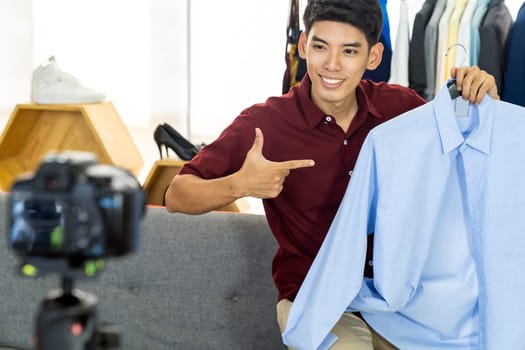 Young asian male online merchant fashion blogger using smart mobile phone to recording live vlog video for review casual wear clothes. Online influcencer on social media concept.