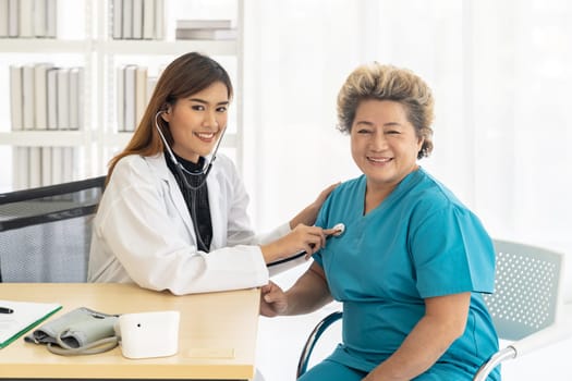 Doctor listens to elderly woman breath with a stethoscope at examination room office in hospital clinic.