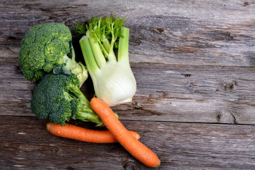 green broccoli, spring onions,fennel and carrots on wooden board