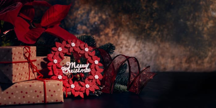 Christmas decoration with Red Poinsettia flowers (Euphorbia Pulcherrima), fir branch and gift boxes on a dark background. Christmas background with copy space. Greeting card.