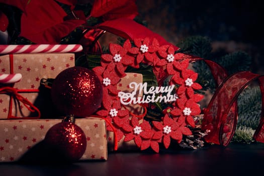 Christmas decoration with Red Poinsettia flowers (Euphorbia Pulcherrima), fir branch and gift boxes on a dark background. Christmas background with copy space. Greeting card.