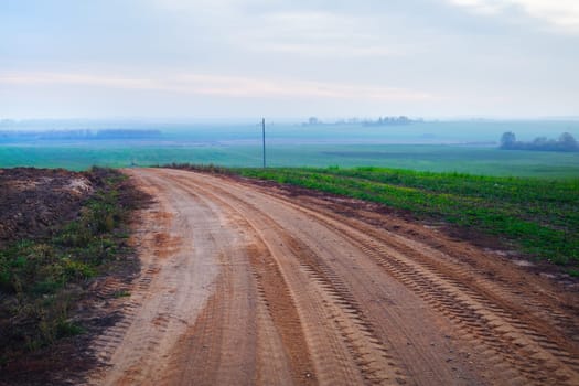 Gravel road turn. Evening in the countryside. Rural landscape.