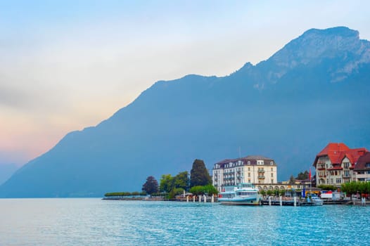 Sunrise landscape with resort embankment at mountain lake, moored touristic boats, Austria