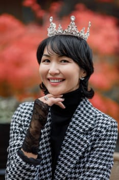 A girl of oriental nationality in a crown and fishnet gloves, laughing playfully