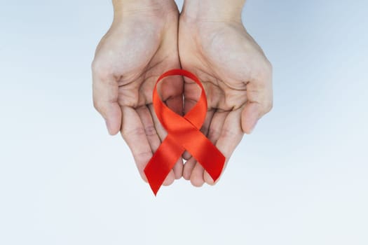 Aids awareness, male hands holding red AIDS awareness ribbon on white background. World Aids Day, Healthcare and medical concept.
