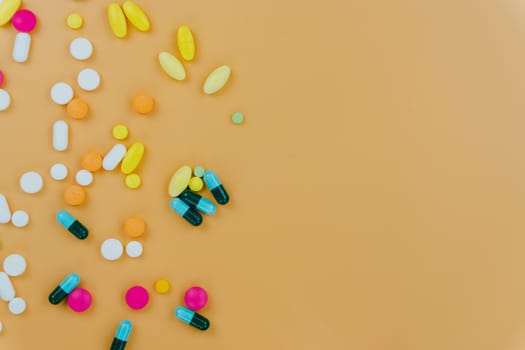 Assorted pharmaceutical medicine pills, tablets and capsules, and bottle on yellow background. Copy space for text, top view.