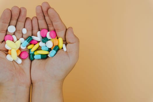 Top view of woman hands holding assorted pharmaceutical medicine pills on yellow background. Hard working and stressful business work overtime, health care concept.