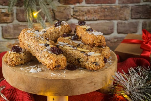 Cereal bars with almonds, coconut and cranberries on a Christmas season table decorated with lights.