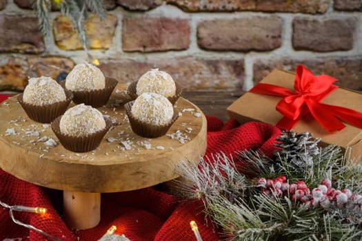 Homemade candies with coconut roasted almonds on a Christmas season table decorated with lights and stars.