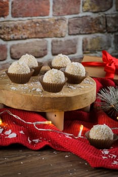 Homemade candies with coconut roasted almonds on a Christmas season table decorated with lights and stars.