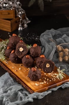 Dark chocolate truffles with hazelnuts over wooden cutting board.