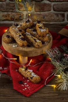 Cereal bars with almonds, coconut and cranberries on a Christmas season table decorated with lights.