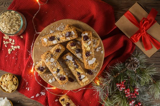 Cereal bars with almonds, coconut and cranberries on a Christmas season table decorated with lights.