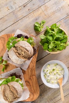 Healthy vegan burger with fresh vegetables and yogurt sauce on rustic kitchen counter top.