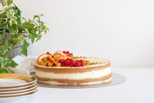 Homemade vanilla birthday cake decorated with orange, peach and gooseberries isolated on table tob. Celebration, party cake.