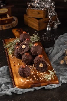 Dark chocolate truffles with hazelnuts over wooden cutting board.