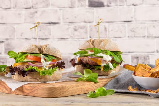 Healthy vegan burger with fresh vegetables and yogurt sauce on rustic kitchen counter top.
