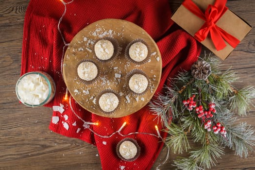 Homemade candies with coconut roasted almonds on a Christmas season table decorated with lights.