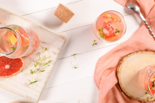 Healthy summer drink grapefruit lemonade with thyme in glasses with ice on a wooden surface.