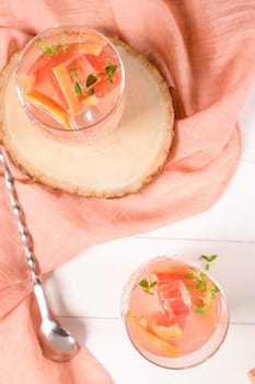 Healthy summer drink grapefruit lemonade with thyme in glasses with ice on a wooden surface.