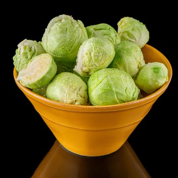 Fresh brussels sprouts on green ceramic bowl isolated on white background.
