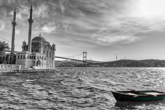Ortakoy Mosque, the Bosphorus bridge and a boat by the pier, black and white image, Istanbul.