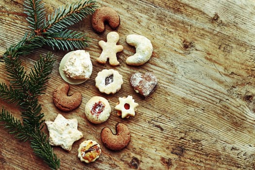 Delicious Christmas cookies and fir branches on a wooden background