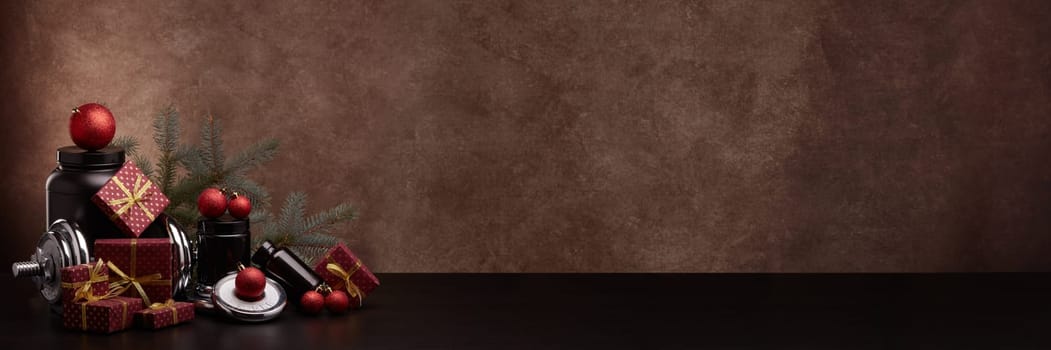 Sports nutrition, sports equipment, fir branch, gifts, Christmas ornaments on dark brown background with copy space. Fitness, sport, healthy lifestyle concept. New Year. Christmas. Banner background