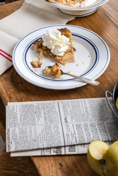 plate with a piece of pie with apples and a newspaper