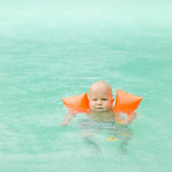 Baby with armbands in swimming pool