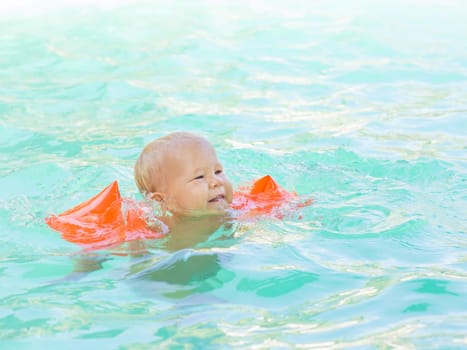 Baby with armbands in swimming pool