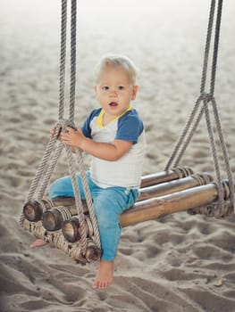 Baby sitting on a bamboo swing