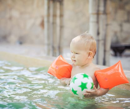 Baby with armbands in swimming pool