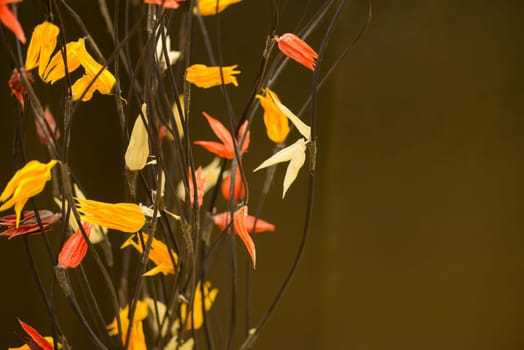 Nice composition of colorful plastic flowers on brown background