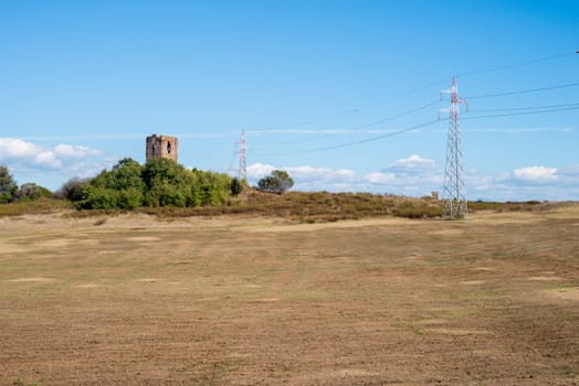 landscape of an ancient tower with power pylons