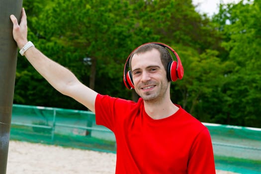 Young joyful Sportsman with red headphones in nature