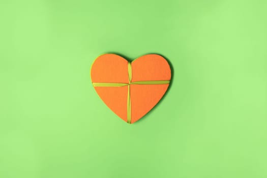 Orange felt heart with ribbon on green cardboard