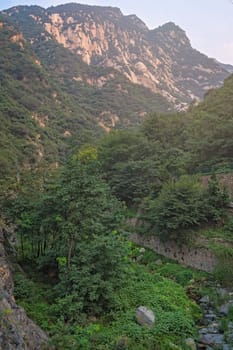 Stream flowing down in a narrow valley in front of the inspiring, sacred and majestic Huashan mountain, famous tourist attractions, Shaanxi province, China