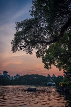 Small wooden boat on the waters of Shanhu or Shan Lake in Guilin town at sunset, Guangxi Province, China