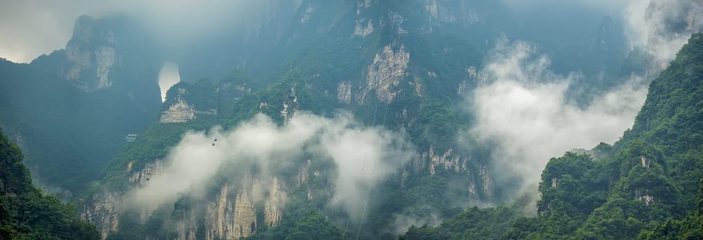 Panoramic view of the famous holy sacred Tianmen mountains covered in early morning fog and mist, Zhangjiajie, China