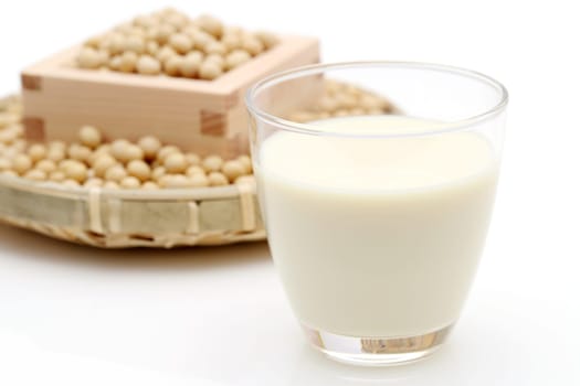Glass of soy milk with soy bean on white background