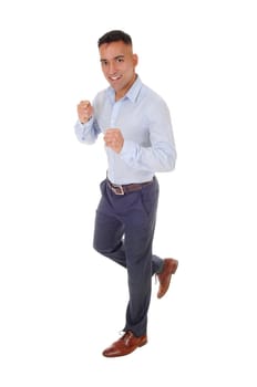 A handsome young man in a blue shirt and dress pants is running in.the studio, isolated for white background.