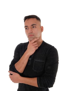 A handsome east Indian business man standing in the studio isolated.over white background, in a black shirt with his hand on his chin.thinking hard.