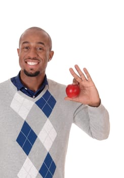 An African American man standing in a sweater, smiling bright and.holding in his hand a red apple, isolated for white background.