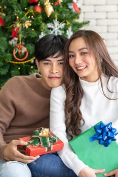 Portrait of couple holding gift box present celebraing Christmas festival holiday in living room with Christmas decoration Ornamental